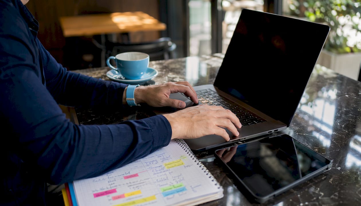 Hands typing on laptop reviewing software cost spreadsheet