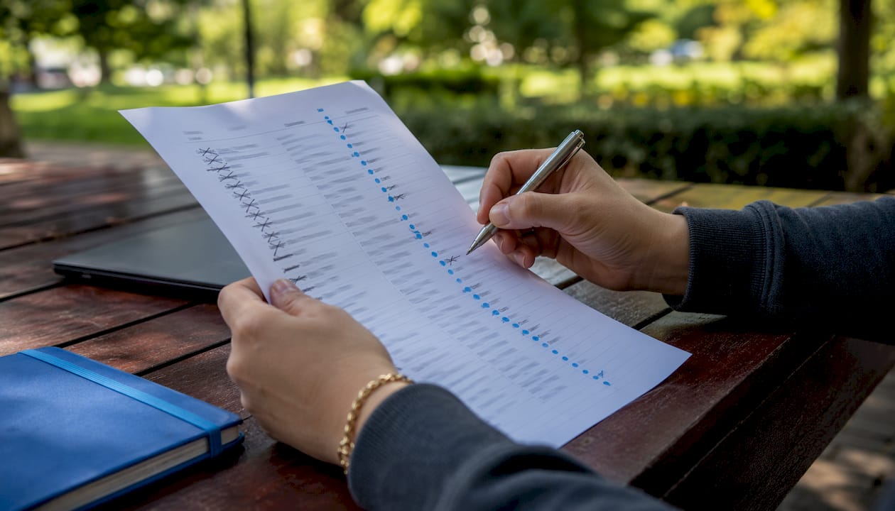 Hands marking invalid emails on printed list