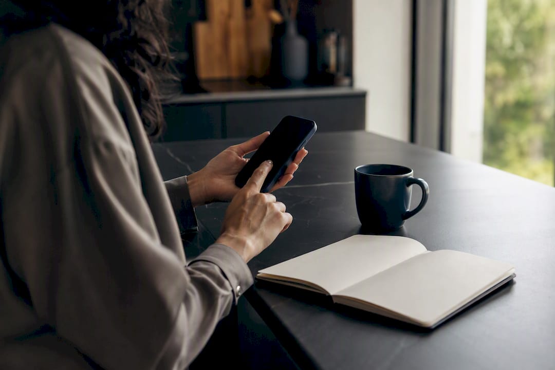 Hands poised to tap smartphone at business desk